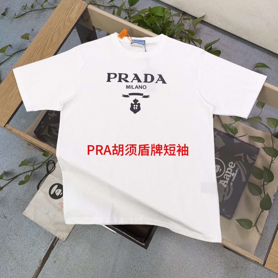 PRA胡须盾牌短袖2024新款PRADA普拉达经典简约字母图案logo印花休闲情侣短袖T恤，独一无二的活性环保面料染色，32支双纱精梳纯棉爽滑手感，纯棉不起球不起毛，面料采用纯棉双纱爽滑面料，质量保证、原厂面料、定制定染、包浆印刷环保不开裂，欢迎对比质量，男女同款！颜色：黑色 白色尺码如下